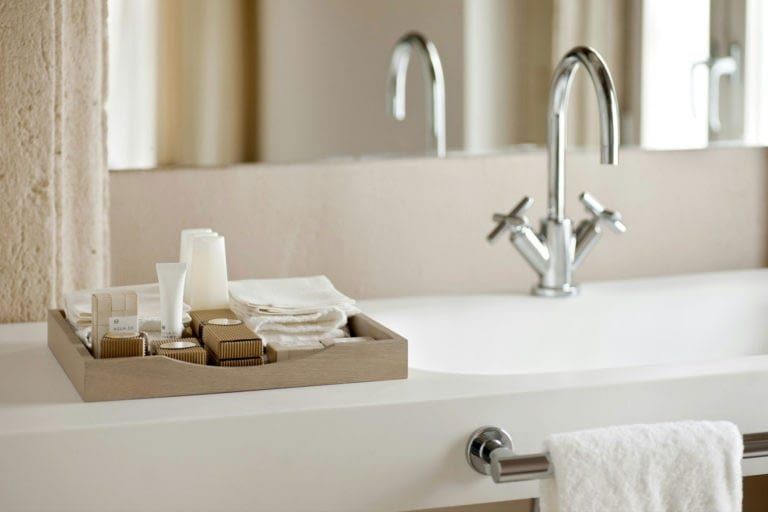 Bathroom basin with chrome tap and a tray of amenities