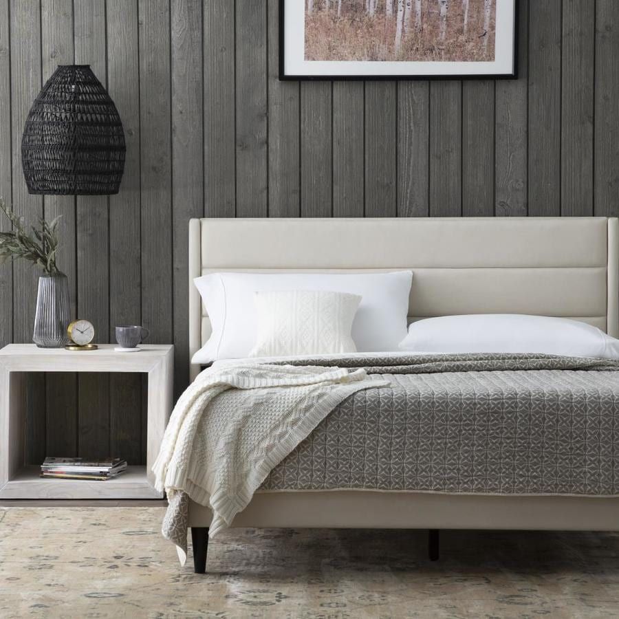 Hotel bedroom with grey linen, white pillows and a bedside lamp