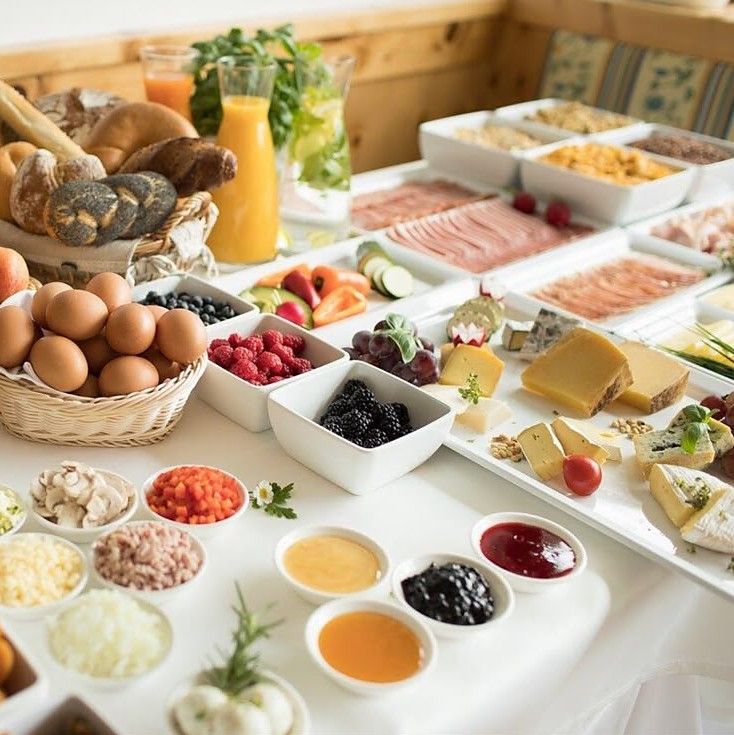 Breakfast buffet with bread rolls, eggs, cheeses, cured meats, berries, jams and fresh juice