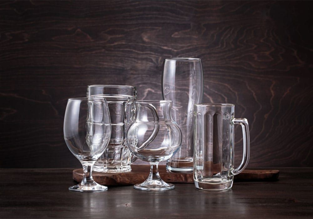 Clear beer glasses and tumblers on a dark wooden table