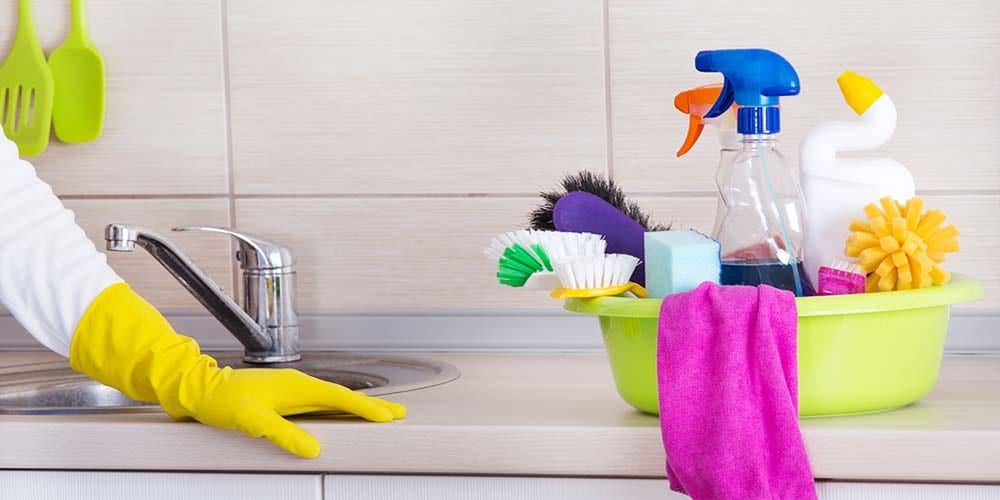 Cleaning products and gloves beside a kitchen sink