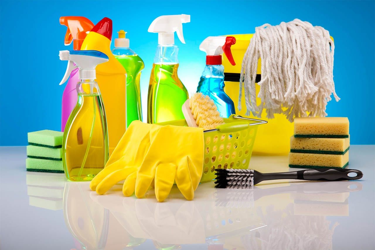 Cleaning sprays, sponges, gloves and a mop on a blue background