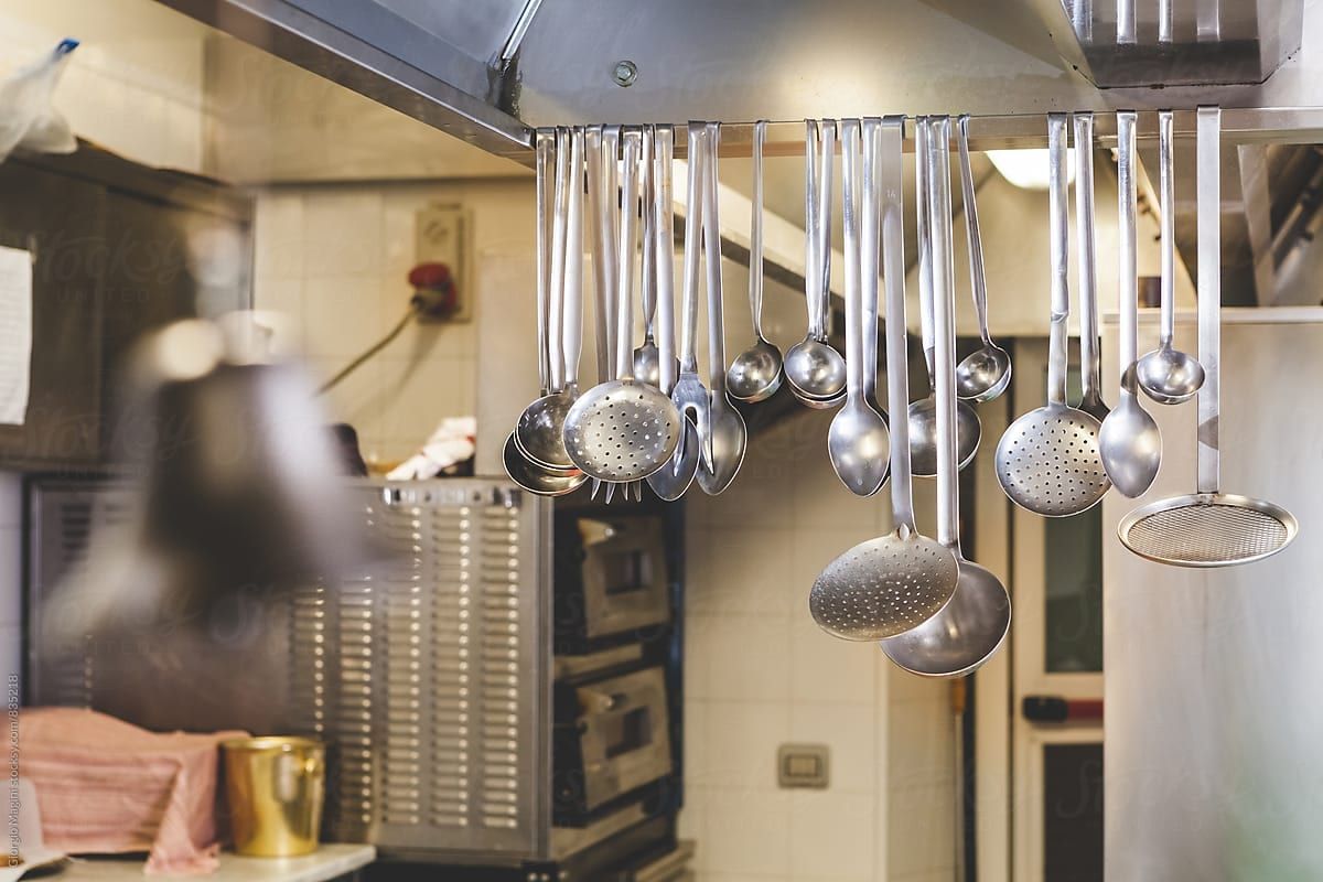 Stainless-steel ladles and utensils hanging in a commercial kitchen