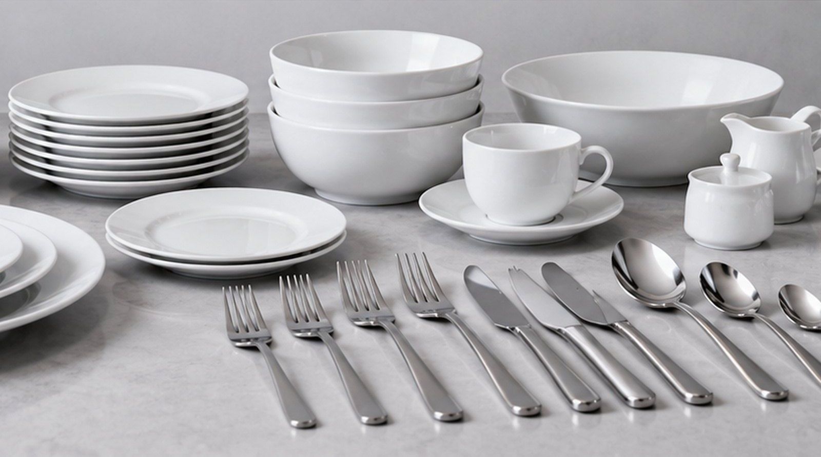 White plates, bowls, cup and saucer with a set of stainless-steel cutlery