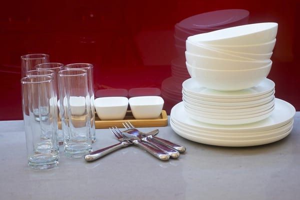 Stacked white plates, bowls and glassware on a red background